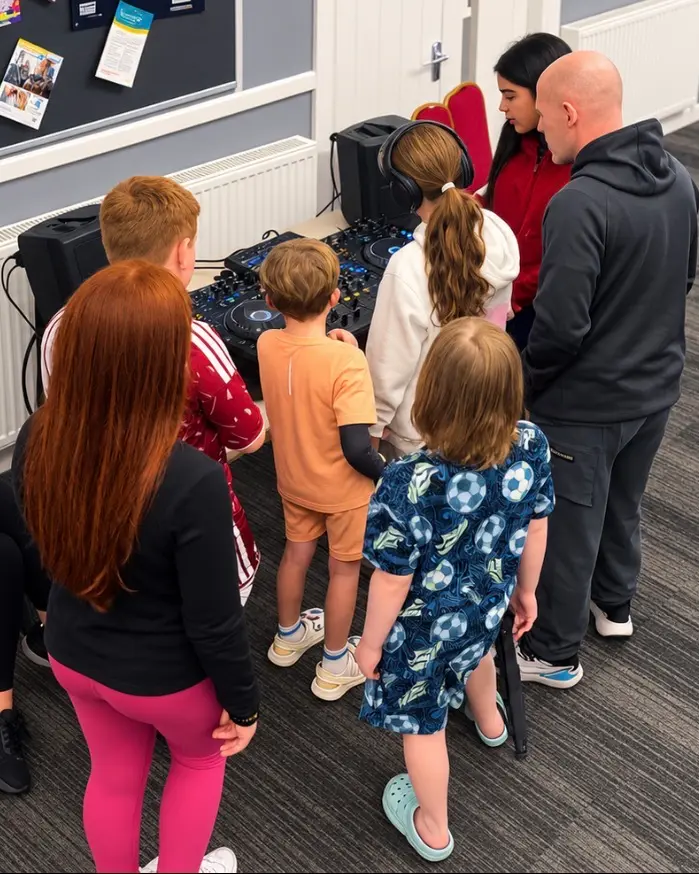 Young people gathered round the DJ decks with a facilitator during a session