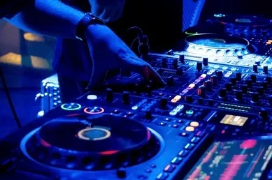 Hands mixing on DJ decks under blue lights