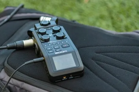 Handheld field recorder resting on a backpack outdoors